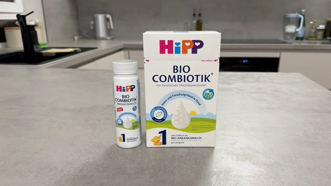 A bottle of HiPP German Stage 1 ready to feed beside a box of HiPP German Stage 1 powder on a kitchen counter, fronts to the camera.